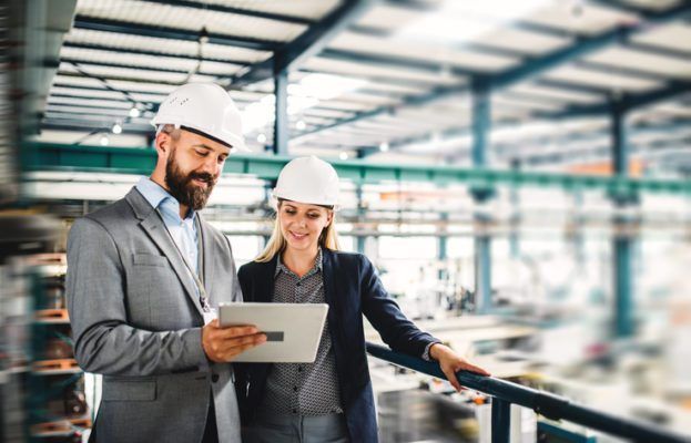 A portrait of a mature industrial man and woman engineer with tablet in a factory.