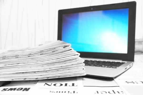 Newspapers and Open Laptop with Blue Screen