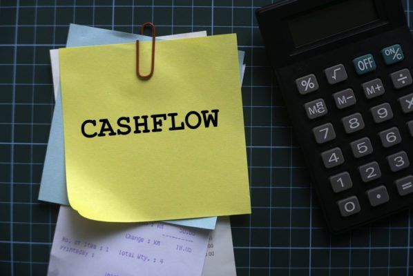 Top view of a calculator and a stack of memo notes written with Cashflow on a green square background.