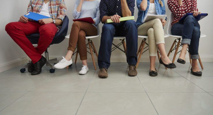 People sitting in chairs waiting in the queue for job interview