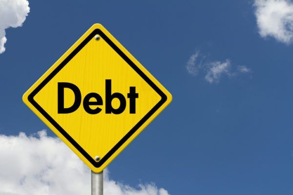 Yellow road sign with the word "debt" against a blue sky with clouds.