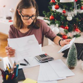 A person reviewing documents at a desk with a calculator, surrounded by festive christmas decorations.