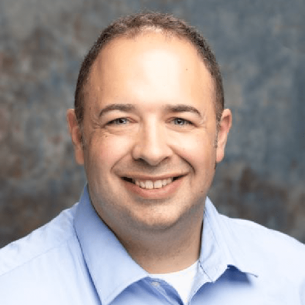 Professional headshot of a smiling man wearing a blue shirt by Nick Skinfill.