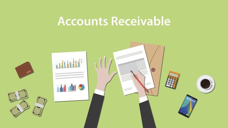 Top view of a workspace with documents labeled "understanding accounts receivable financing," including charts and reports, accompanied by a person's hands working with a pen, alongside office supplies such as a calculator,