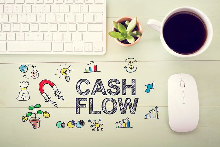 Cash Flow concept with workstation on a light green wooden desk.