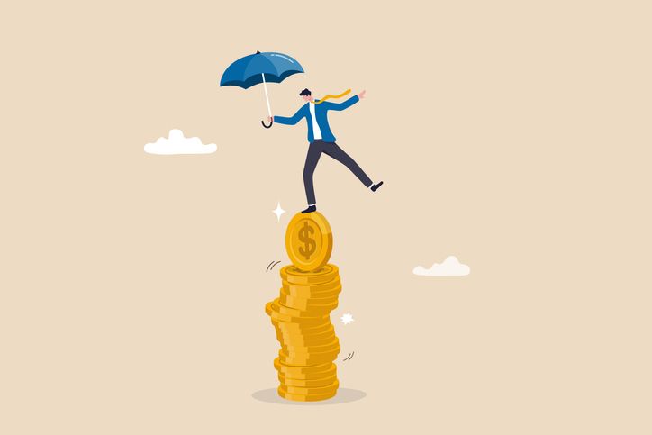 Strong financial foundation businessman hold umbrella balance on unstable coins stack.