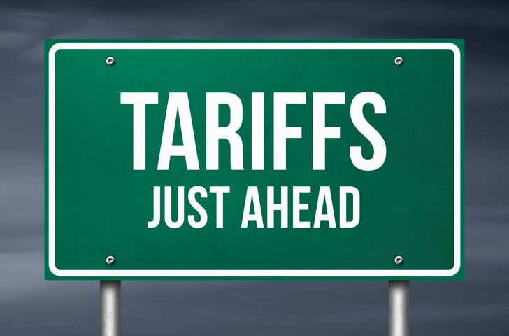 Tarrifs just ahead - green road sign warning. How invoice factoring can ease tariff burdens.